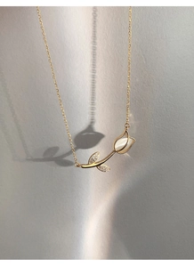 Close-up of golden tulip necklace with white shell pendant and sparkling gemstones