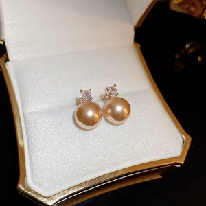 Close-up of champagne pearl earrings with zircon inlay in a velvet jewelry gift box