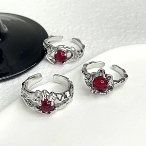 Close-up of irregular silver rings featuring lava texture and red circular gemstone