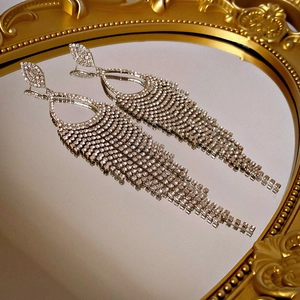 Macro shot of silver crystal tassel earrings on a vintage gold mirror reflective surface