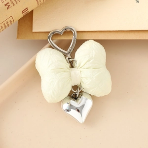 Close-up of a quilted yellow bow with a silver heart pendant and heart-shaped metal clip
