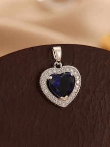 Macro detail of heart pendant featuring deep blue gemstone and sparkling zircon halo