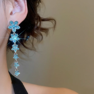 Close-up of elegant long tassel earrings with blue floral crystals and silver finish