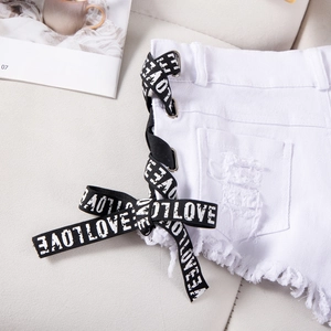 Dettaglio degli shorts di jeans bianchi con nastri LOVE stringati e orlo a frange