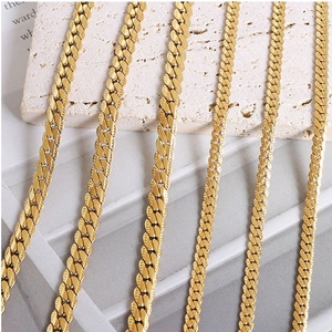 Detailed view of golden curb chains with fish-scale texture on minimalist stone background
