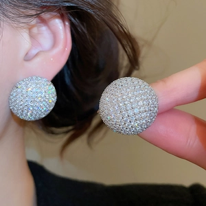 Gros plan de grandes boucles d'oreilles rondes pavées de zircons blancs étincelants