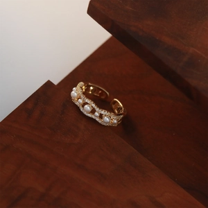 Detailed view of wave-shaped gold ring featuring five small pearls and pave zircon stones