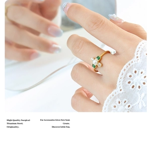 Detail of titanium steel gold ring with white pearl, green gemstone and zircon accents