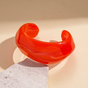 Detailed macro view of orange marble-patterned resin cuff bracelet on stone texture
