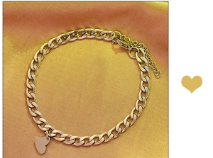 Detail of gold heart pendant bracelet with flat link chain and lobster clasp on silk