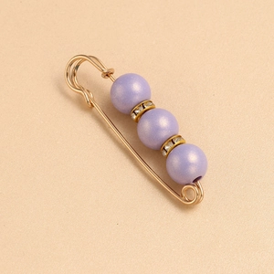 Detail of purple matte beads and crystal rings on golden safety pin brooch for waist