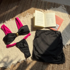 Detail view of black bikini set with mesh skirt and gold buckle on a resort straw mat