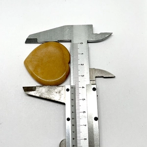 Close-up of heart-shaped yellow jade worry stone being measured with a caliper