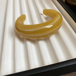 Detail of amber acrylic C-shaped cuff bracelet with smooth polished resin finish