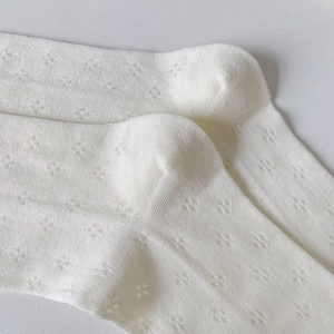 Close-up of white breathable mesh mid-tube socks with intricate hollow-out knit patterns