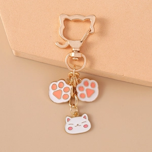 Detail of cute cat paw enamel charms on gold kitten-shaped keychain hook