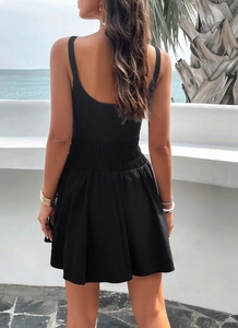 Outdoor shot of a black sleeveless mini dress with elastic waist and an elegant U-back design