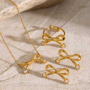 Detailed set of 18k gold plated bow jewelry with heart zircons on natural stone