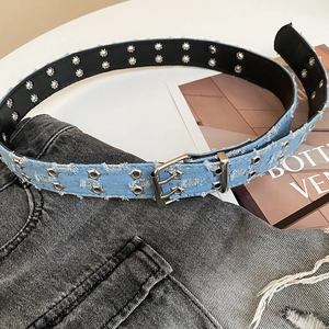 Detail showing frayed light blue denim belt with rows of silver metal eyelets for Y2K style