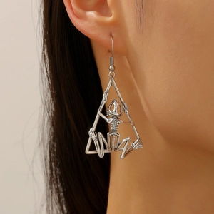 Detalle de pendiente de calavera gótica plateada en marco triangular con modelo