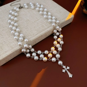 Macro shot of tiered pearl necklace with a vintage sparkling rhinestone cross pendant