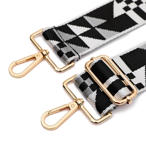 Detail of wide fabric bag strap with geometric patterns and gold metal swivel hooks