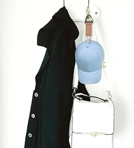 Detail showing a light blue baseball cap hanging on a wall via a durable clip and strap