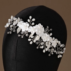 Macro detail of bridal hair comb with handmade clay flowers, crystal beads and white pearls