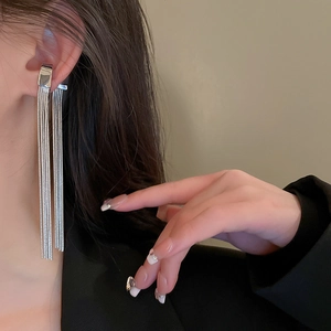 Close-up of a silver long tassel ear cuff worn by a model for a chic fashion style