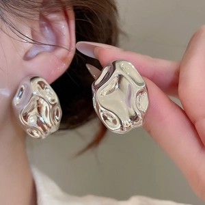 Close-up of oversized silver crinkled acrylic geometric earrings worn on model