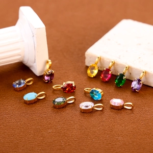 Colorful zircon waterdrop pendants with gold-plated bases on elegant stone props