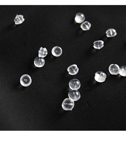 Macro shot of transparent silicone earring backs displayed on a black textured fabric surface