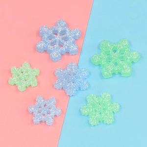 Dettaglio di ciondoli a fiocco di neve in resina glitterata blu e verde per il fai-da-te