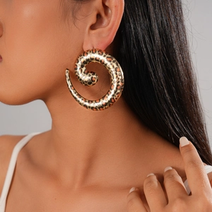 Detail view of large spiral leopard print earrings worn by a model in a side profile