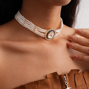 Detailansicht eines mehrlagigen Perlen-Chokers mit Kristallanhänger an einem Model.