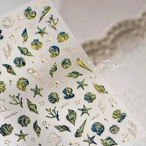 Macro detail of 3D ocean nail stickers with embossed shells and gold metallic outlines