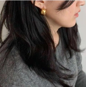 Close-up of a woman wearing gold chubby hollow hoop earrings in a minimalist French style