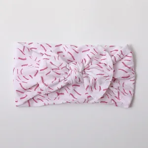 Close-up of soft nylon baby headband featuring a pink baseball stitch printed bow