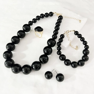 Flat lay of vintage black pearl necklace set with matching bracelet and earrings