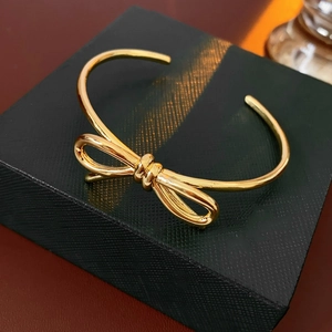 Dettaglio di un bracciale rigido dorato a fiocco su una confezione regalo nera di lusso