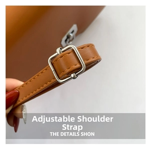 Detail of adjustable brown leather shoulder strap with silver buckle and litchi texture