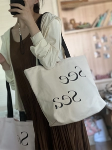 Detail shot of the large canvas tote bag featuring black lettering and long straps
