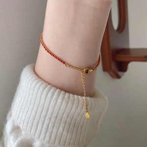Close-up of handmade red cord bracelet with 18K gold plated titanium lobster clasp