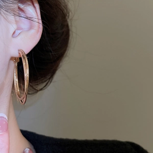 Close-up of rose gold double hoop earrings with glitter texture on woman model