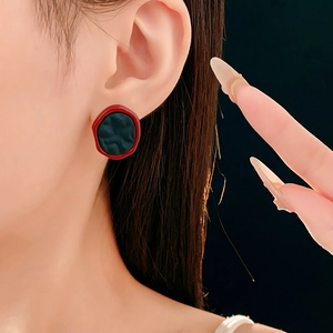 Gros plan d'un mannequin portant des boucles d'oreilles rondes rouges et noires de style vintage