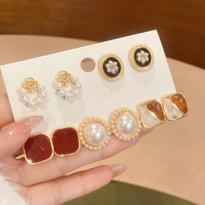 Macro shot of elegant vintage earring set featuring pearls and gold flower designs