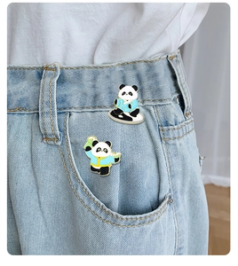 Detail of two cute enamel panda brooches in blue costumes pinned on denim jeans