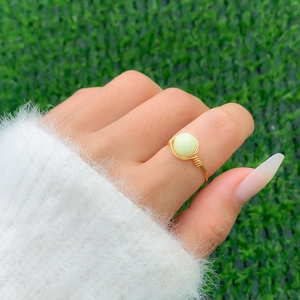Detailed macro view of handmade wire-wrapped gold ring with a soft green stone