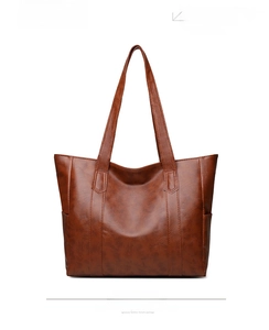 Close-up of brown faux leather tote bag showing lychee grain texture and long shoulder straps