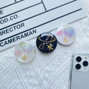 Detailed view of three galaxy themed phone grips with gold star patterns and glitter